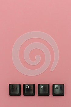 Love concept with keyboard letters on pink background.  Vertical view