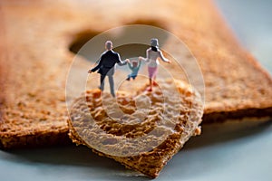 Love Concept. Miniature of Happy Family Walking on Burned Sliced Toasted Bread with a Heart shape