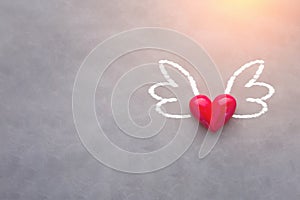 Love concept with red heart object with wings drawing on grey ba