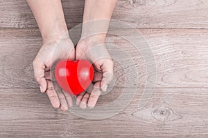 Love Concept : Woman hands holding red heart on brown wooden tab