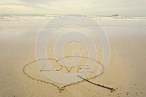 Love concept , written by hand in sand on a sea beach with soft wave.