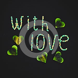 `With love` of confetti and kiwi fruit on dark background. Love concept. Flat lay, top view