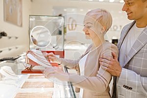 Love couple choosing gold chain in jewelry store