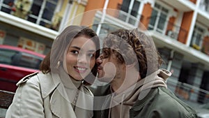 Love couple feeling happy together outdoor. Man whispering to woman on street.