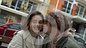 Love couple feeling happy together outdoor. Man whispering to woman on street.