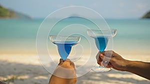 The love couple is holding a glass of blue curacao cocktail, on