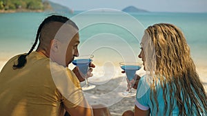 The love couple is holding a glass of blue curacao cocktail, on