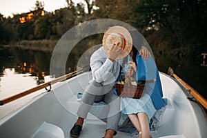 Love couple kissing in a boat on lake at sunset