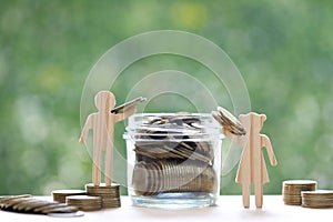 Love couple putting a coin into the glass bottle on green background, Finance, Saving for lover or family and save money for