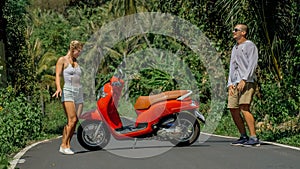 Love couple on red motorbike in white clothes, sunglasses on forest road trail trip. Dancing road. Two caucasian tourist