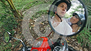 Love couple on red motorbike in white clothes to go on forest road trail trip. Two caucasian tourist woman man drive on