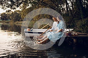 Love couple sitting on the pier on quiet lake