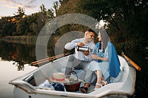 Love couple with thermos in a boat on quiet lake