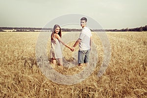 Love couple walking in field holding hands