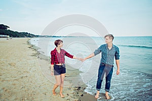 Love couple walking on sea shore holding hands in beach vacation. Concept of lovers happy moments on holiday. Boyfriend and girlfr