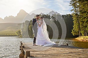 Love, dance and a married couple on a pier over a lake in nature with a forest in the background after a ceremony