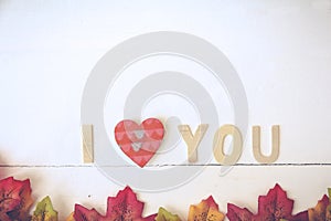 Love day concept. The wooden text remain to valentine`s day with maple leaf and white background.valentine day, february14