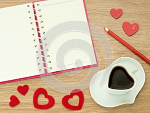 Love diary. Valentines day background with heart shape of cup with coffee, red hearts, book for diary and color pencils on wood fl