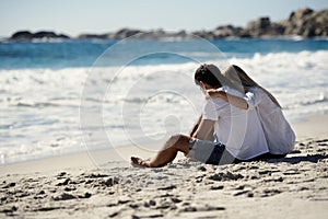 Love, embrace and couple sitting on beach for date, outdoor bonding and tropical holiday. Romance, man and woman at sea