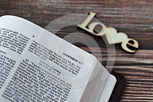 Love for enemies verse in open Holy Bible Book on wooden background