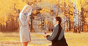 - kneeled man proposing a woman to marry, giving red box with ring, happy smiling young