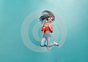 Love,enjoy and lifestyle concept.Beautiful energy girl with white headphones listening to music laughs and jump on blue background