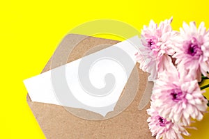 Love envelope with blank letter and pink chrysanthemum flowers on bright yellow bacground.