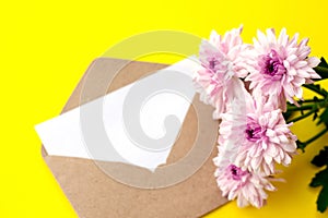 Love envelope with blank letter and pink chrysanthemum flowers on bright yellow bacground