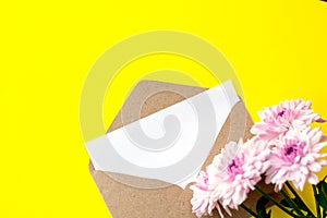 Love envelope with blank letter and pink chrysanthemum flowers on bright yellow bacground.