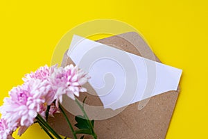 Love envelope with blank letter and pink chrysanthemum flowers on bright yellow bacground.