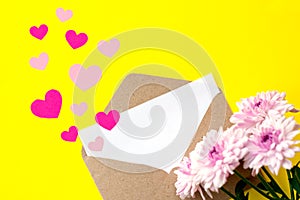 Love envelope with blank letter and pink chrysanthemum flowers with pink hearts on bright yellow bacground.