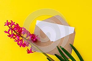 Love envelope with blank letter and pink hyacinth flowers on bright yellow bacground.
