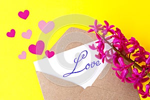 Love envelope and letter with written word love and pink hyacinth flowers with pink hearts