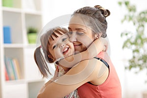 Love and family people concept - happy mother and child daughter hugging at home photo