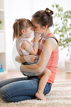 Love and family people concept - happy mother and child daughter hugging at home