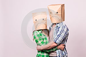 Love, family and relationship problems concept - unhappy couple covering their sad faces with paper bag over white