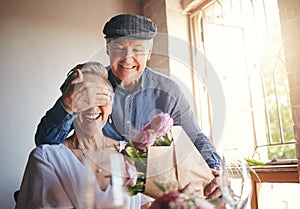 Love, flowers and surprise gift with elderly couple in celebration of a birthday or anniversary, happy and romantic