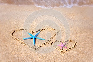 Love formula is drawn on the sand by the sea.Two starfishes Valentine`s Day