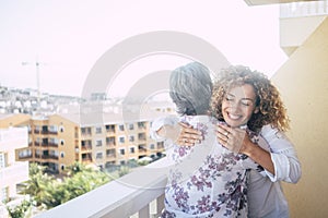 Love for friends or family concept with curly beautiful happy middle age woman hugging a mature grey hair senior lady on the