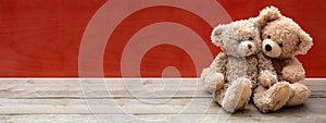 Love, friendship concept, tight hug. Teddy bears couple on wooden floor, red wall background, banner