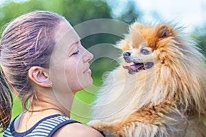 Love, friendship between owner and dog. smiling girl looking at handsome fluffy spitz. happy Pomeranian in hands of woman. female