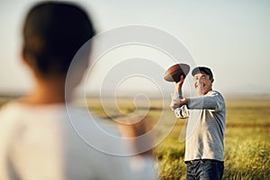 We love the game. father and son playing football on an open field.
