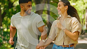 Love, happy and interracial couple running in a park together on a date in nature and bonding in happiness outdoors