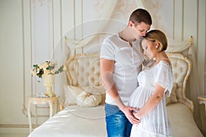 Love and happy pregnancy.Gentle beautiful pregnant couple near tulle curtains