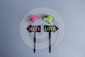 Love or hate symbol. Concept word love or hate on beautiful signpost with two arrows. Beautiful grey background. Toy hands are