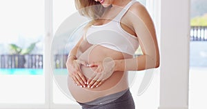 Love, heart hands and fitness with stomach of pregnant woman for training, workout and wellness. Exercise, happy and