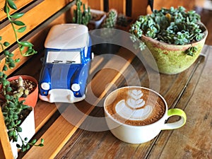 Love heart latte art coffee cup on the vintage wooden table with blue Ceramic car