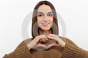 Love, heart shape, peace. Sign, gesture or symbols. Portrait of cute attractive smiling brunette woman, girl shows heart