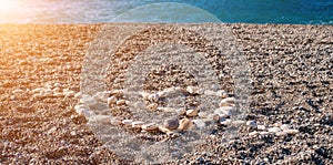 Love heart shape on sand made out of white pebbles, symbol of love on the beach with sea background. Valentine day