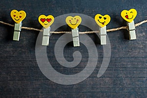 Love Hearts yellow emotions or emoticons clothespins or pegs on a rope on wooden rustic vintage background